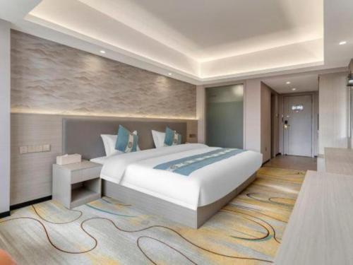 a bedroom with a large white bed and a rug at Lijiang Waika Hotel in Lijiang