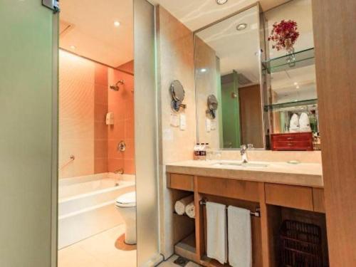 a bathroom with a sink and a toilet and a mirror at Huzhou Zhebei Hotel in Huzhou