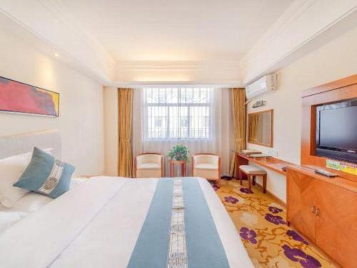 a hotel room with a large bed and a television at Lijiang Waika Hotel in Lijiang