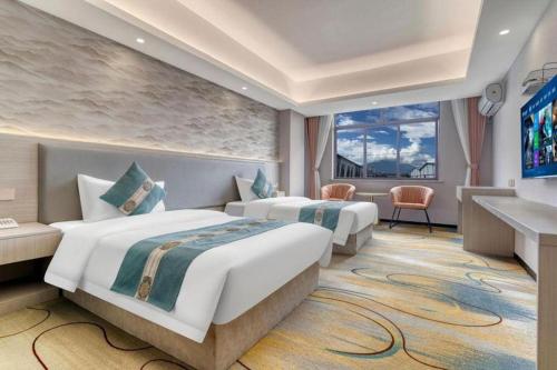 a hotel room with two beds and a tv at Lijiang Waika Hotel in Lijiang