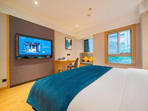 a bedroom with a large bed with a television on a wall at Xian Katie Eastman Hotel in Xi'an