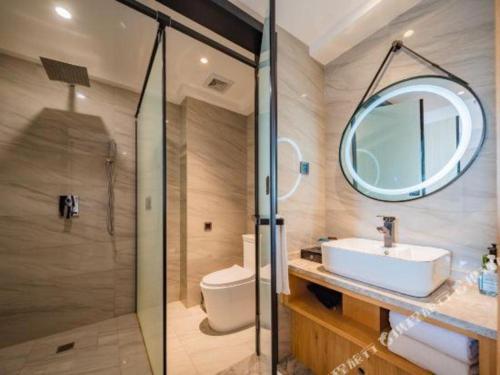 a bathroom with a sink and a toilet and a mirror at Xian Katie Eastman Hotel in Xi'an