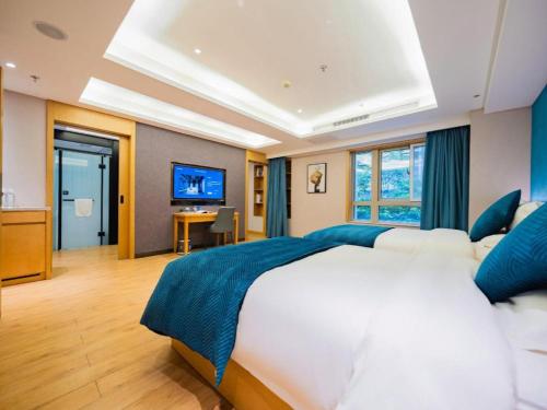 a bedroom with a large white bed and a television at Xian Katie Eastman Hotel in Xi'an