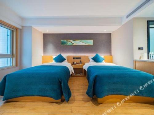 two beds in a bedroom with blue and white at Xian Katie Eastman Hotel in Xi'an