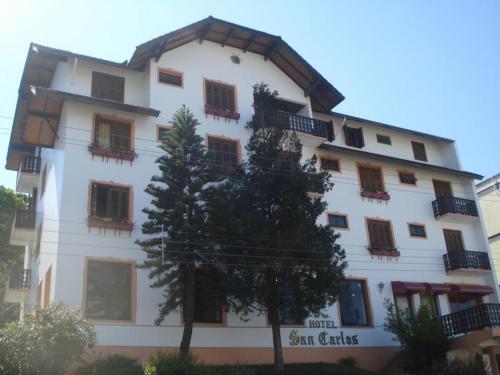 a white building with a tree in front of it at Hotel San Carlos in Carlos Barbosa