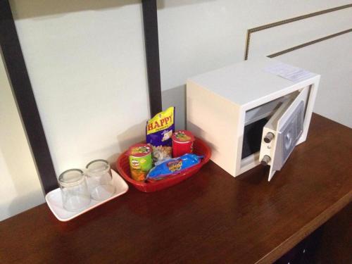 a microwave on a wooden table with food and drinks at Horizon Hotel in Olongapo