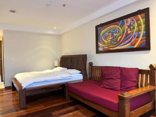 a bed and a bench in a room with a painting at Mango Valley Hotel in Olongapo