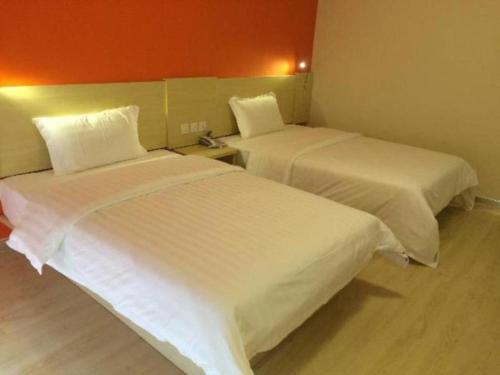 two beds in a hotel room with white sheets at 7 Days Inn Beijing Shunyi Development Area Mordern Motor City in Beijing