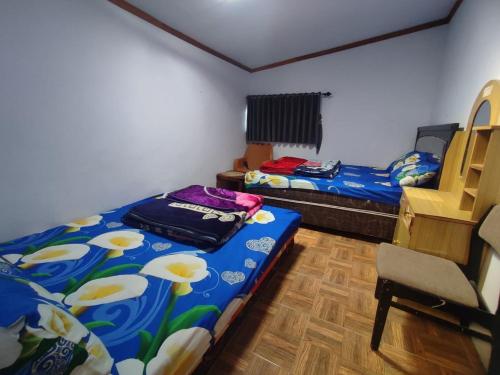 a room with two beds and a chair in it at Elen Homestay by ABM in Bromo