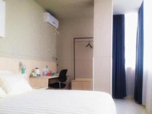 a bedroom with a bed and a desk with a chair at Jinjiang Inn Wuhan Zhonghua Road HuangheLou Branch in Wuhan