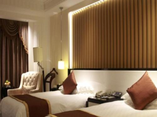 a hotel room with two beds and a chair at Tongxiang Inspirock Hotel in Jiaxing