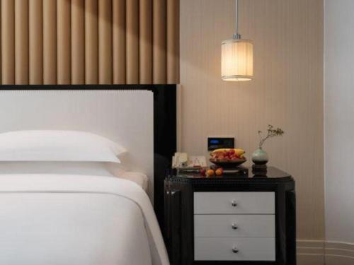 a bedroom with a bed and a table with a bowl of fruit on it at Tongxiang Inspirock Hotel in Jiaxing