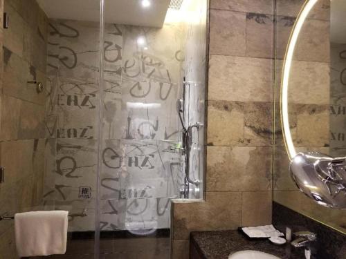 a bathroom with a shower with a sink and a mirror at Jai Alai Hotel in Macau