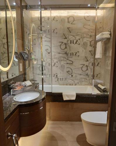 a bathroom with a shower and two sinks and a tub at Jai Alai Hotel in Macau