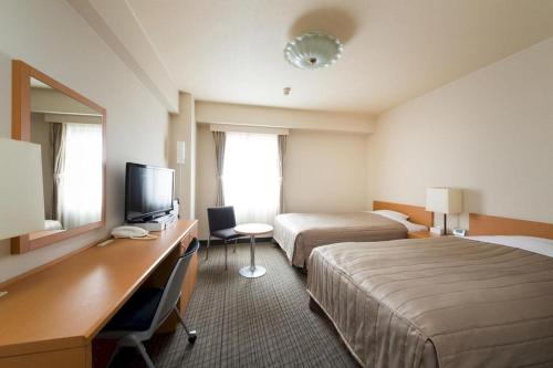 a hotel room with two beds and a desk at Sapporo Hotel Yamachi in Kotoni