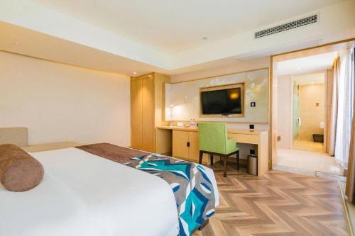 a hotel room with a bed and a desk and a television at James Joyce Coffetel Chengdu Jichang Road Shenxianshu in Chengdu