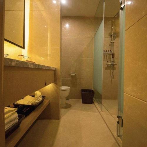 a bathroom with a toilet and a glass shower at James Joyce Coffetel Chengdu Jichang Road Shenxianshu in Chengdu