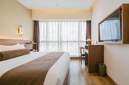 a hotel room with a bed and a desk and a television at James Joyce Coffetel Chengdu Jichang Road Shenxianshu in Chengdu