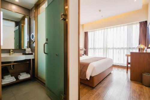 a bedroom with a bed and a bathroom with a sink at James Joyce Coffetel Chengdu Jichang Road Shenxianshu in Chengdu