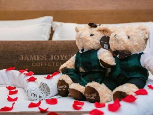 two teddy bears sitting next to each other on a bed at James Joyce Coffetel Chengdu Jichang Road Shenxianshu in Chengdu