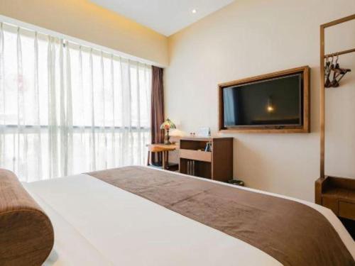 a hotel room with a bed and a flat screen tv at James Joyce Coffetel Chengdu Jichang Road Shenxianshu in Chengdu