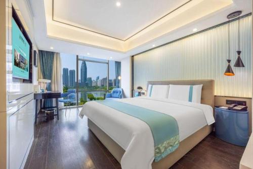a hotel room with a large bed and a balcony at Xana Hotelle Wuhan Lingjiao Lake Wanda Plaza Branch in Wuhan