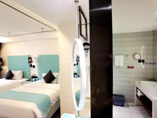a bedroom with two beds and a sink and a mirror at Xana Lite Korla Shihua Avenue Longquehe in Korla