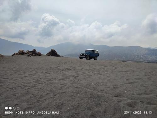 a blue jeep parked in the middle of a desert at Elen Homestay by ABM in Bromo