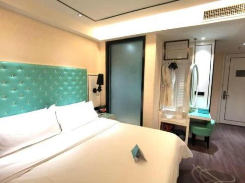 a bedroom with a large white bed with a green headboard at Xana Lite Korla Shihua Avenue Longquehe in Korla