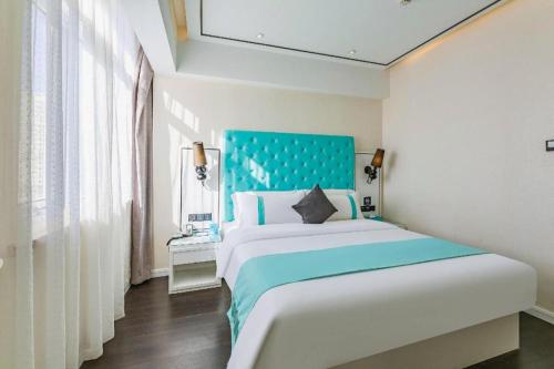a bedroom with a large bed with a blue headboard at Xana Hotelle Shijiazhuang Zhongchu Plaza Shizhuang Metro Station in Shijiazhuang