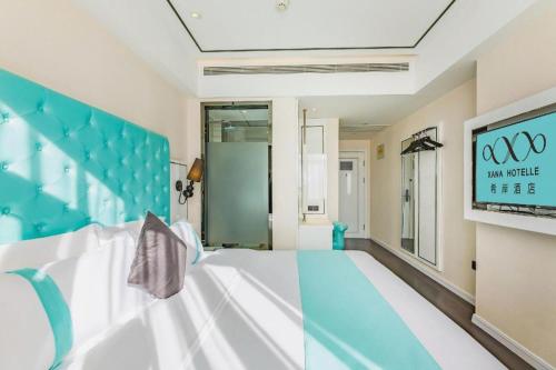 a bedroom with a blue and white bed and a tv at Xana Hotelle Shijiazhuang Zhongchu Plaza Shizhuang Metro Station in Shijiazhuang