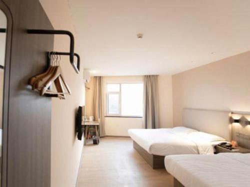 une chambre d'hôtel avec deux lits et une fenêtre dans l'établissement 7 Days Inn Tianjin Binhai Passenger Station Huabei Ceramics, à Binhai