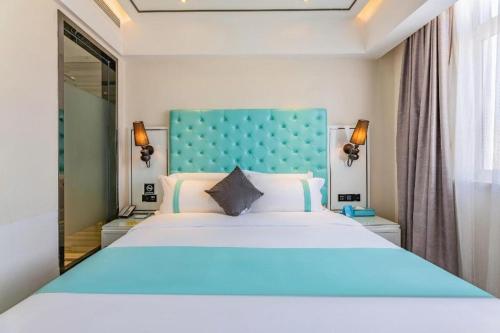 a bedroom with a large bed with a blue headboard at Xana Hotelle Shijiazhuang Zhongchu Plaza Shizhuang Metro Station in Shijiazhuang