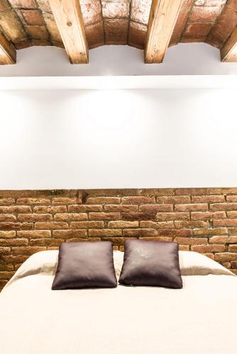 a bedroom with a brick wall and a bed with two pillows at Radas in Barcelona