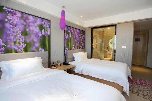 two beds in a room with purple flowers on the wall at Lavande Hotels Changzhi City God Temple in Changzhi
