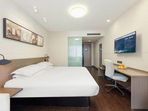 a bedroom with a white bed and a desk and a computer at Jinjiang Inn Select Tianjin Xiaobailou Metro Station in Tianjin