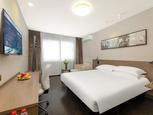 a hotel room with a large white bed and a desk at Jinjiang Inn Select Tianjin Xiaobailou Metro Station in Tianjin