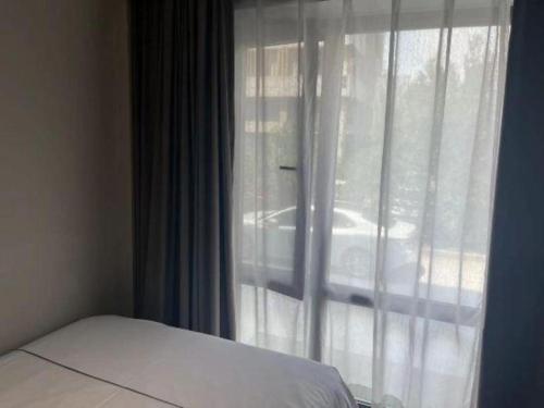 a bedroom with a window with a white curtain at Magnotel Harbin Songbei Wanda Wenlvcheng in Harbin