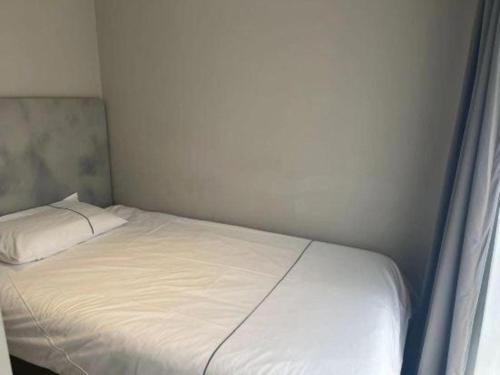 a small bedroom with a white bed and a window at Magnotel Harbin Songbei Wanda Wenlvcheng in Harbin