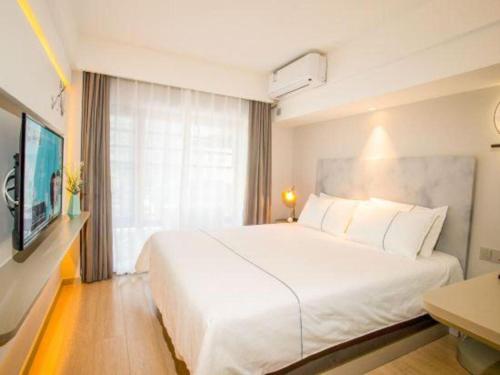 a bedroom with a large white bed and a window at Magnotel Harbin Songbei Wanda Wenlvcheng in Harbin