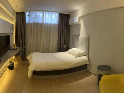 a bedroom with a white bed and a window at Magnotel Harbin Songbei Wanda Wenlvcheng in Harbin