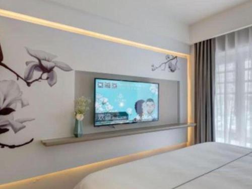 a bedroom with a flat screen tv on the wall at Magnotel Harbin Songbei Wanda Wenlvcheng in Harbin