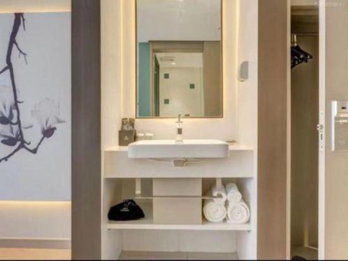 a bathroom with a sink and a mirror at Magnotel Harbin Songbei Wanda Wenlvcheng in Harbin