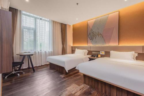 a hotel room with two beds and a desk at IU Hotel Qingdao Golden Beach Xuejiadao Metro Station in Huangdao