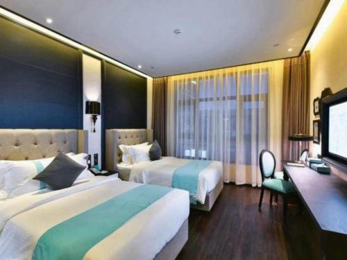a hotel room with two beds and a flat screen tv at Xana Hotelle Chengdou Xindu Sanhechang Metro Station in Chengdu