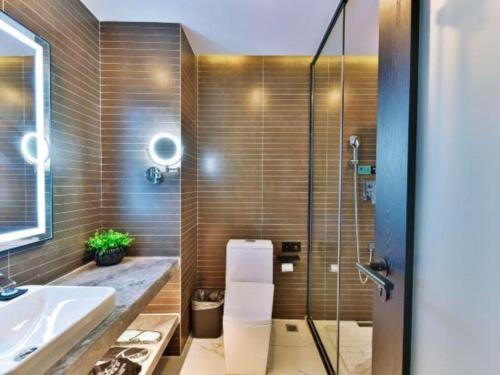 a bathroom with a sink and a glass shower at Xana Hotelle Chengdou Xindu Sanhechang Metro Station in Chengdu