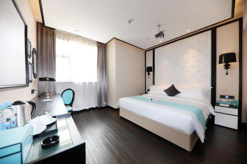a hotel room with a large bed and a desk at Xana Hotelle·Tianshui Shangyi Plaza in Tianshui