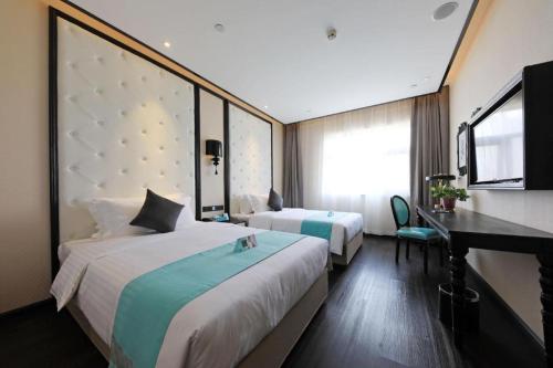 a hotel room with two beds and a desk at Xana Hotelle·Tianshui Shangyi Plaza in Tianshui