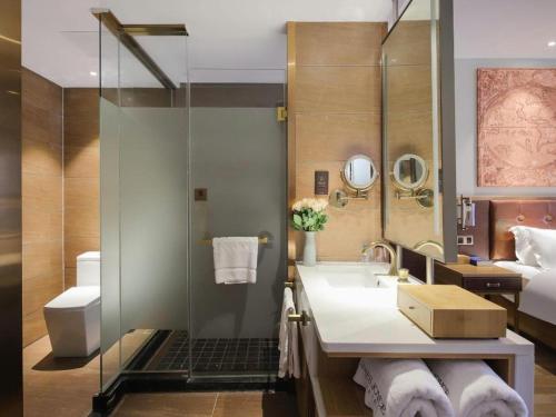 ein Badezimmer mit Waschbecken und Dusche und ein Bett in der Unterkunft James Joyce Coffetel Zhengzhou CBD Exhibition Center Provincial People's Hospital in Zhengzhou