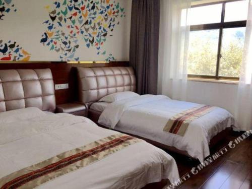 two beds in a hotel room with a window at Shell Linzhi Bayi Area G318 Shuangyong Road Hotel in Nyingchi
